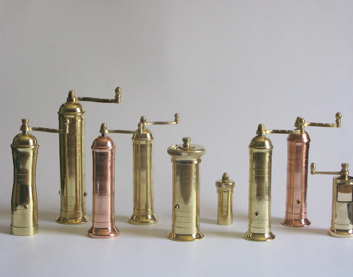 Collection of Atlas Alexander Greek brass and copper pepper mills on a white background