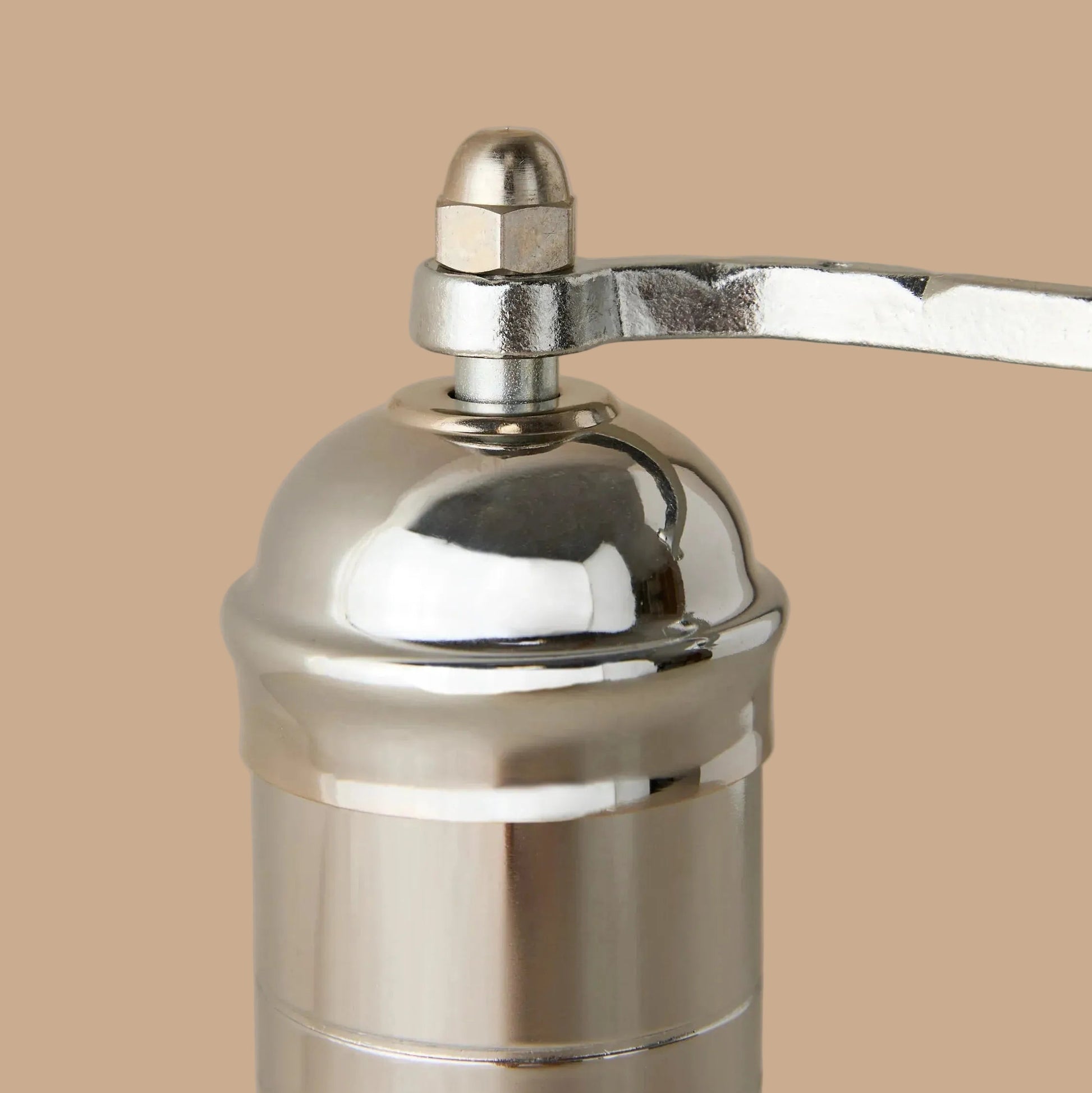Close-up of a metallic pepper grinder on a beige background
