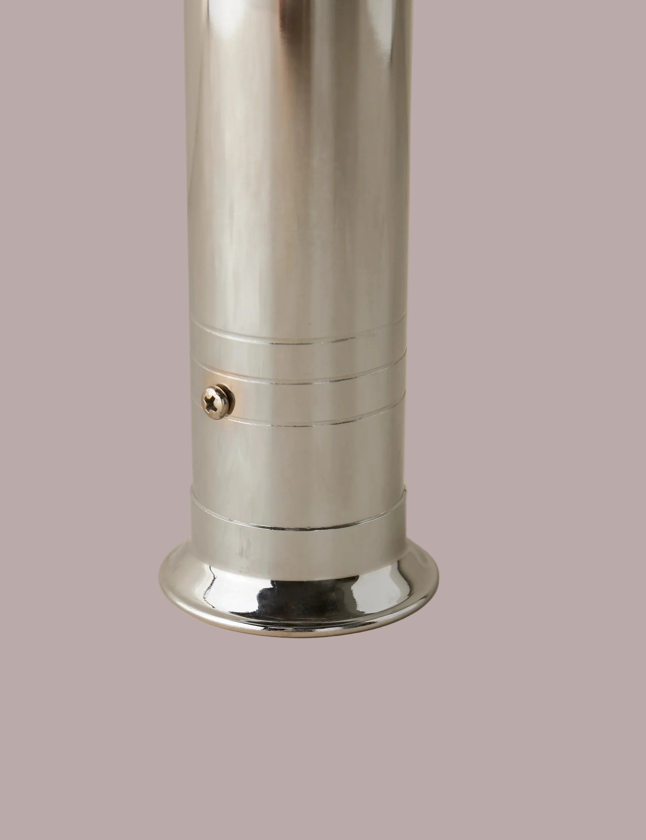 Metallic cylindrical object on a beige background