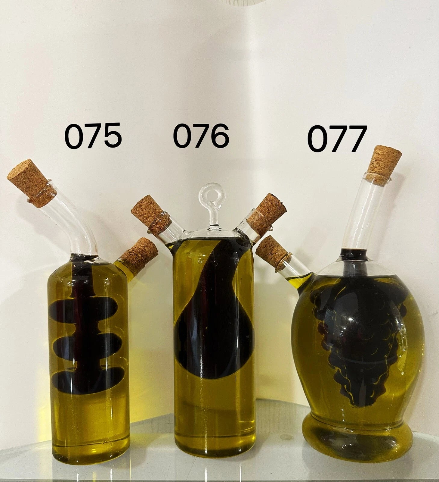 Three glass bottles with cork stoppers containing a yellow liquid on a white background.