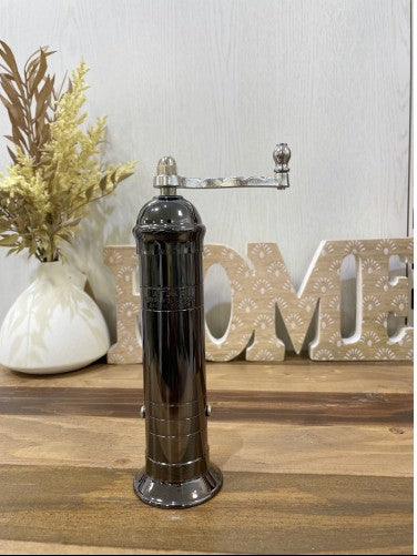 Decorative pepper grinder on a wooden surface with 'HOME' letters in the background