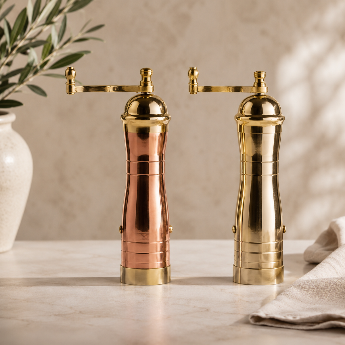 Gold and copper pepper mills on a wooden surface with a neutral background