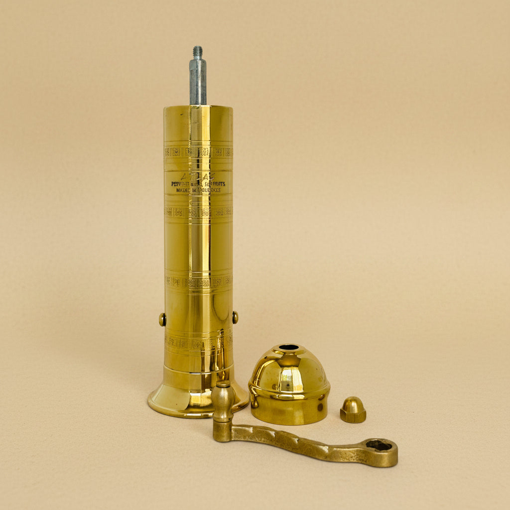 Brass pepper grinder with attached lid on a white background