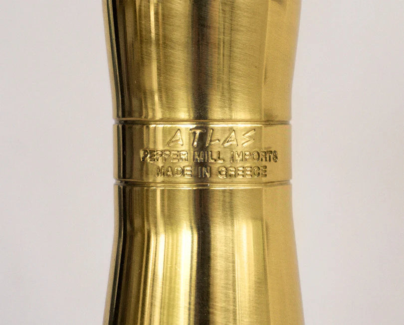 Brass pepper mill with 'Atlas Pepper Mill Imports' branding on a light gray background