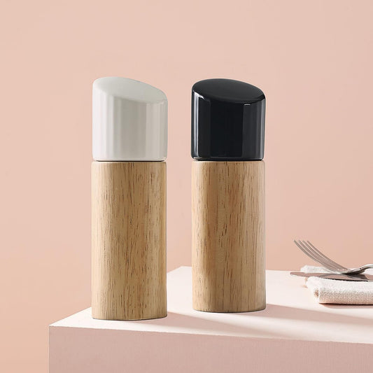 Two modern cylindrical containers with light wood bases, one with a white cap and one with a black cap, displayed on a pink pedestal against a soft pink background.