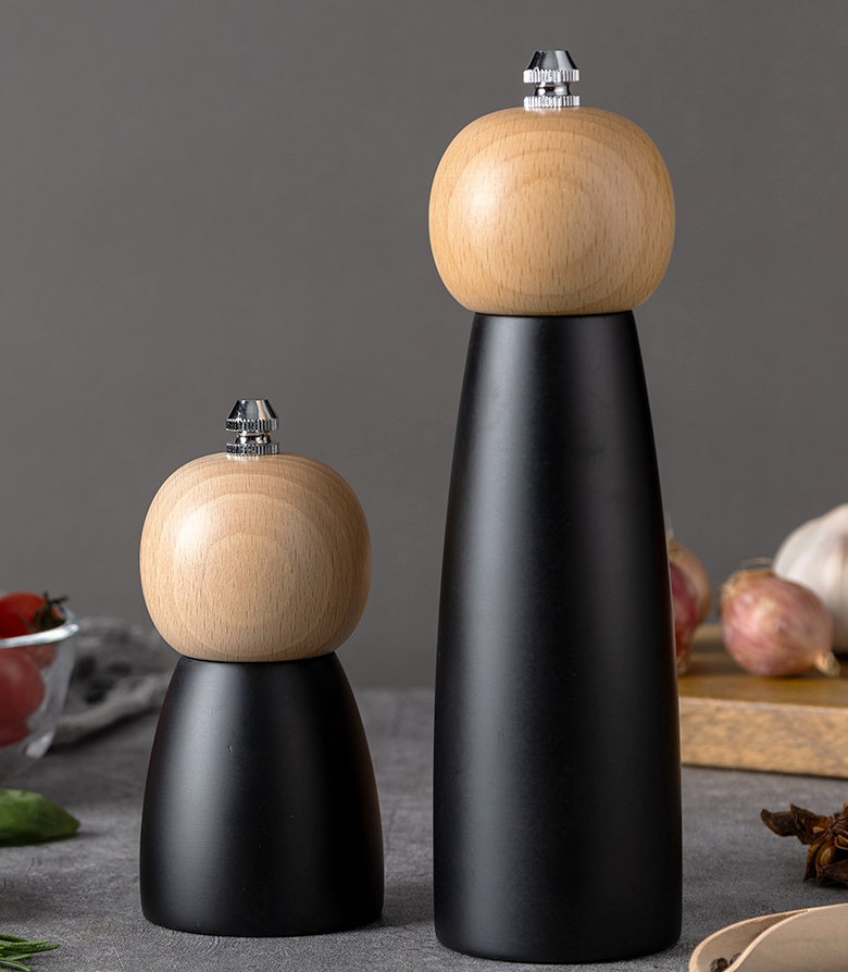 Two pepper mills with wooden tops and black bases on a gray surface.