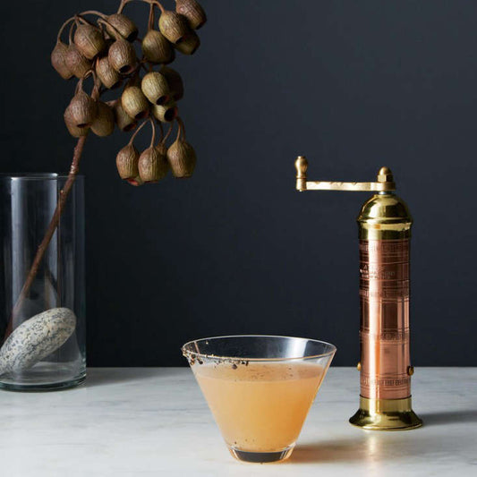 Cocktail in a glass with a copper cocktail mixer on a dark background Peppermill Imports