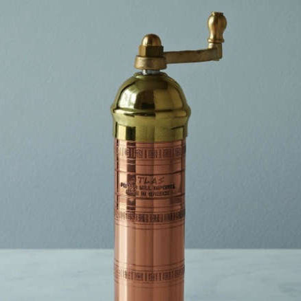 Copper and brass pepper grinder on a gray background