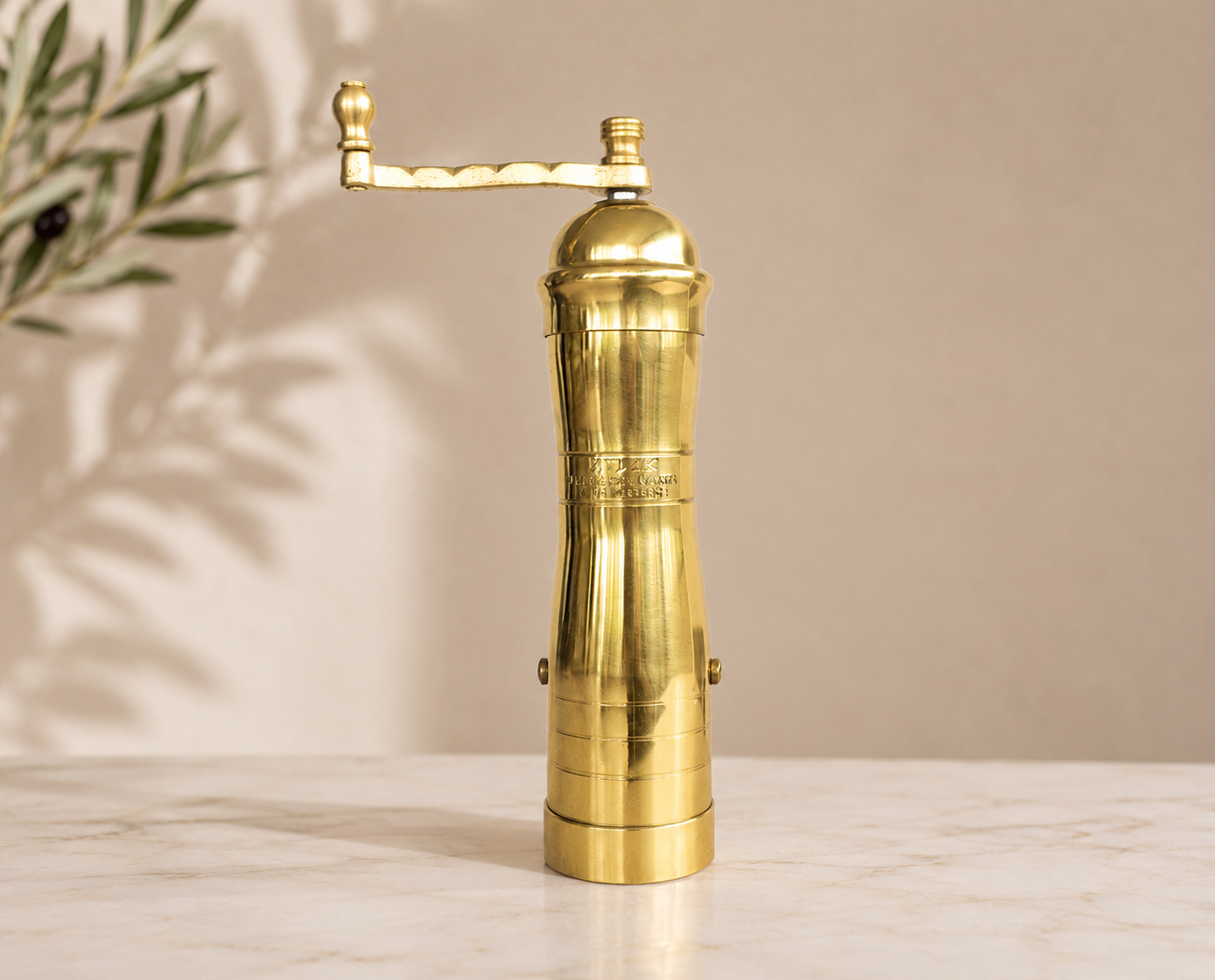 Gold pepper grinder on a marble surface with a beige background