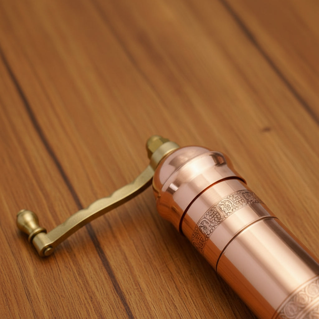 Copper and brass manual coffee grinder on a marble surface
