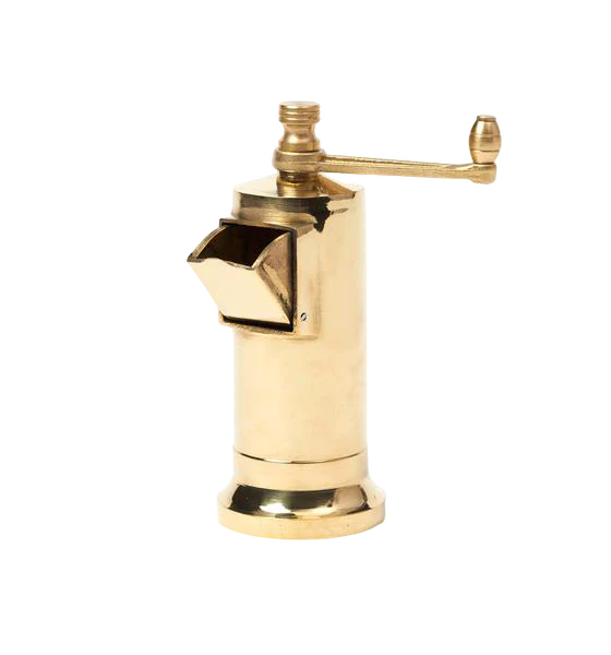 Gold-colored Atlas Pepper Mill with a side crank handle, placed on a marble countertop with ground black pepper sprinkled around.