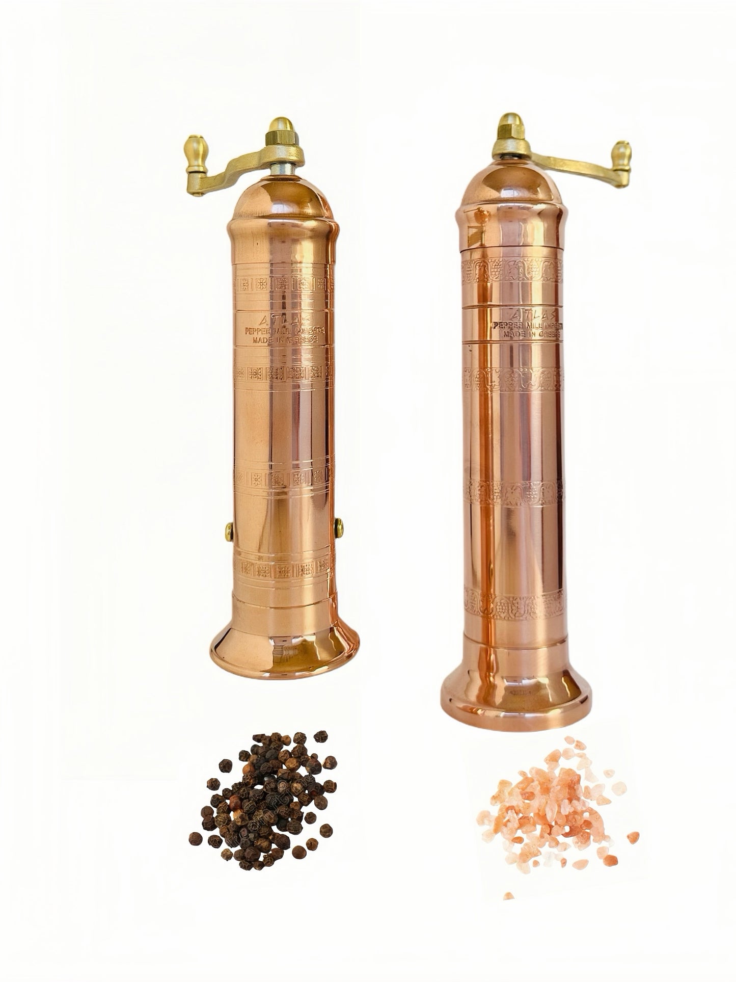 Two copper pepper mills with black and pink peppercorns on a white background